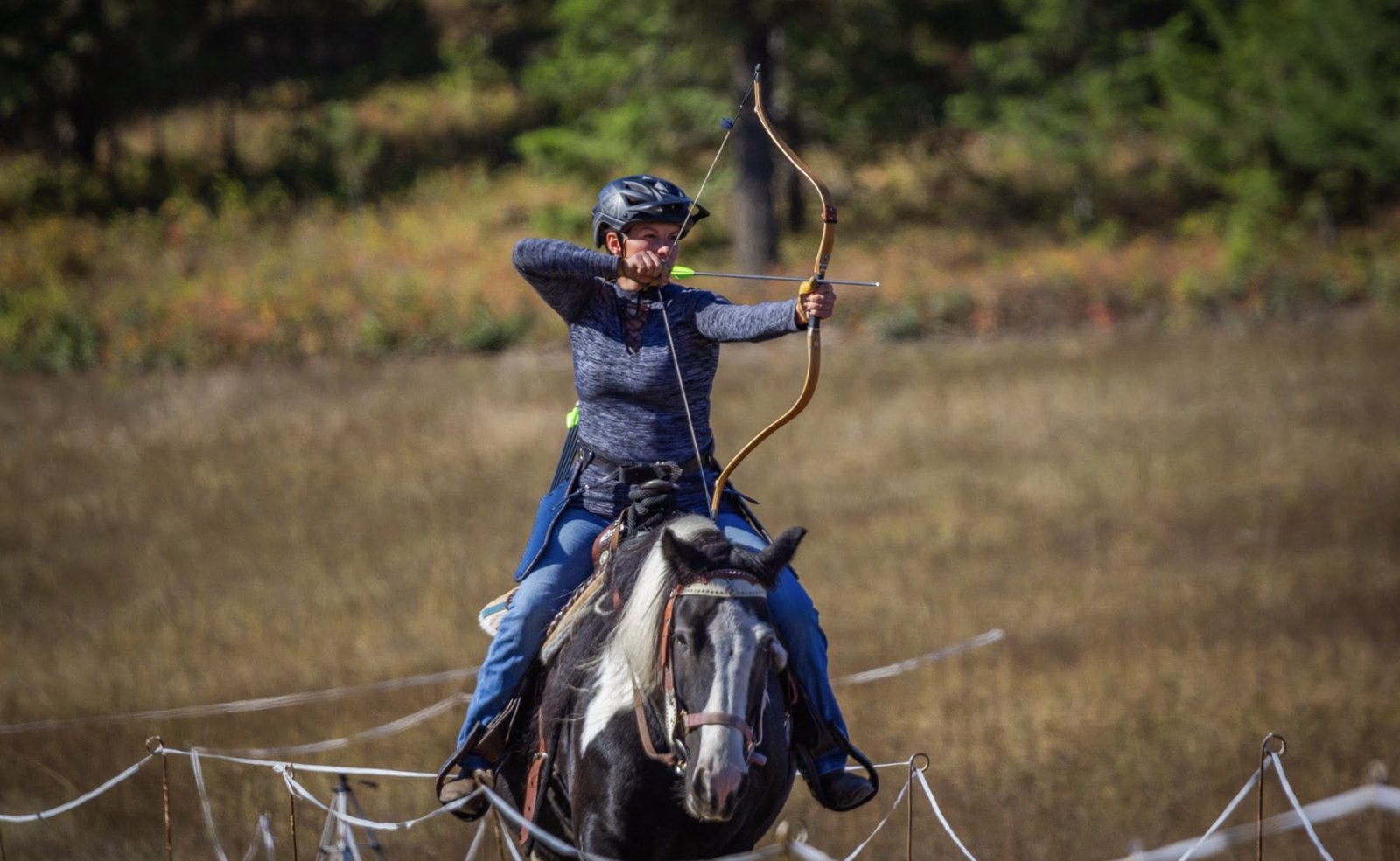 Cathy drawing a bow at full gallop in mounted archery competition